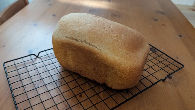 Loaf of homemade bread cooling on a metal rack