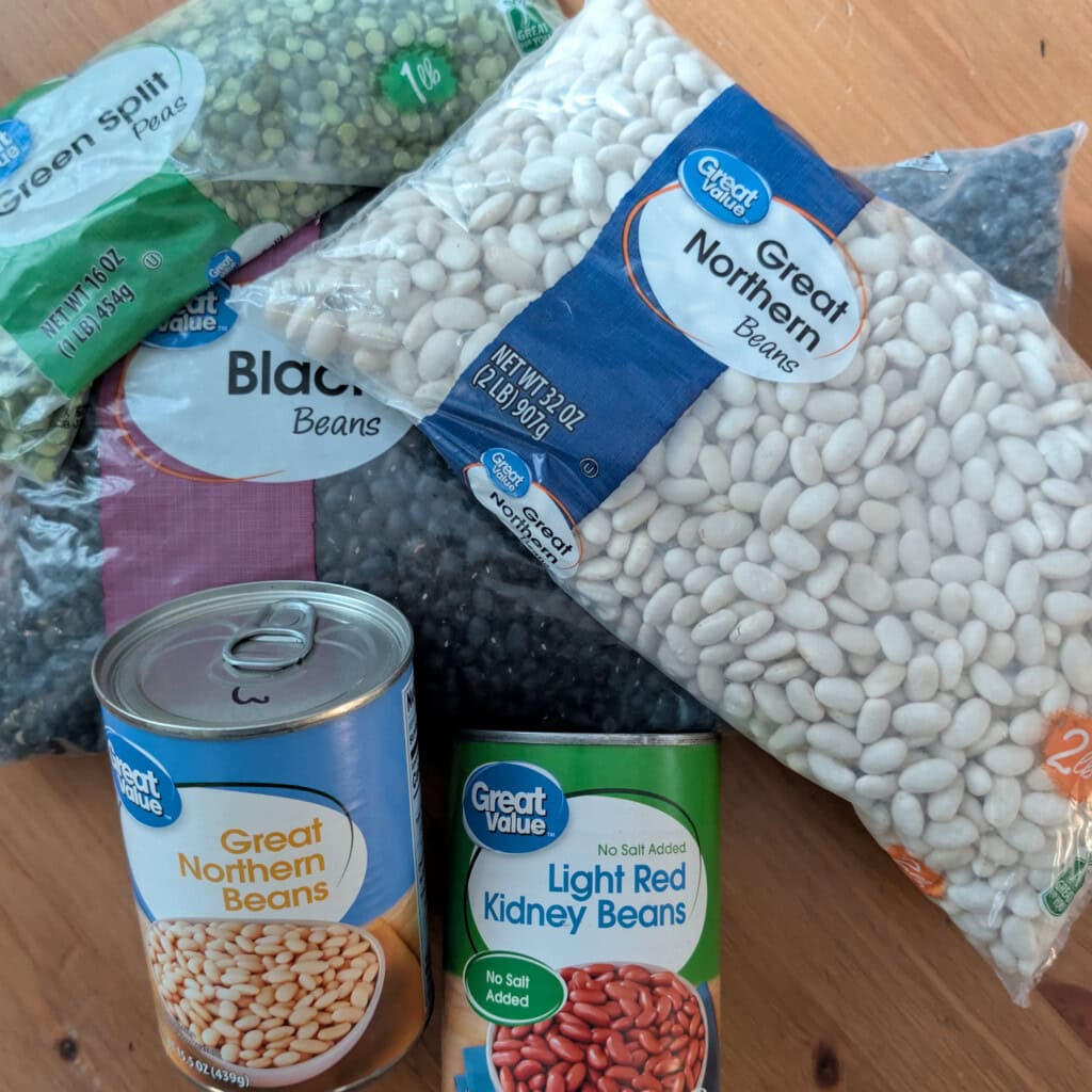 Bags of dried beans laying on a table with a few cans of beans on top