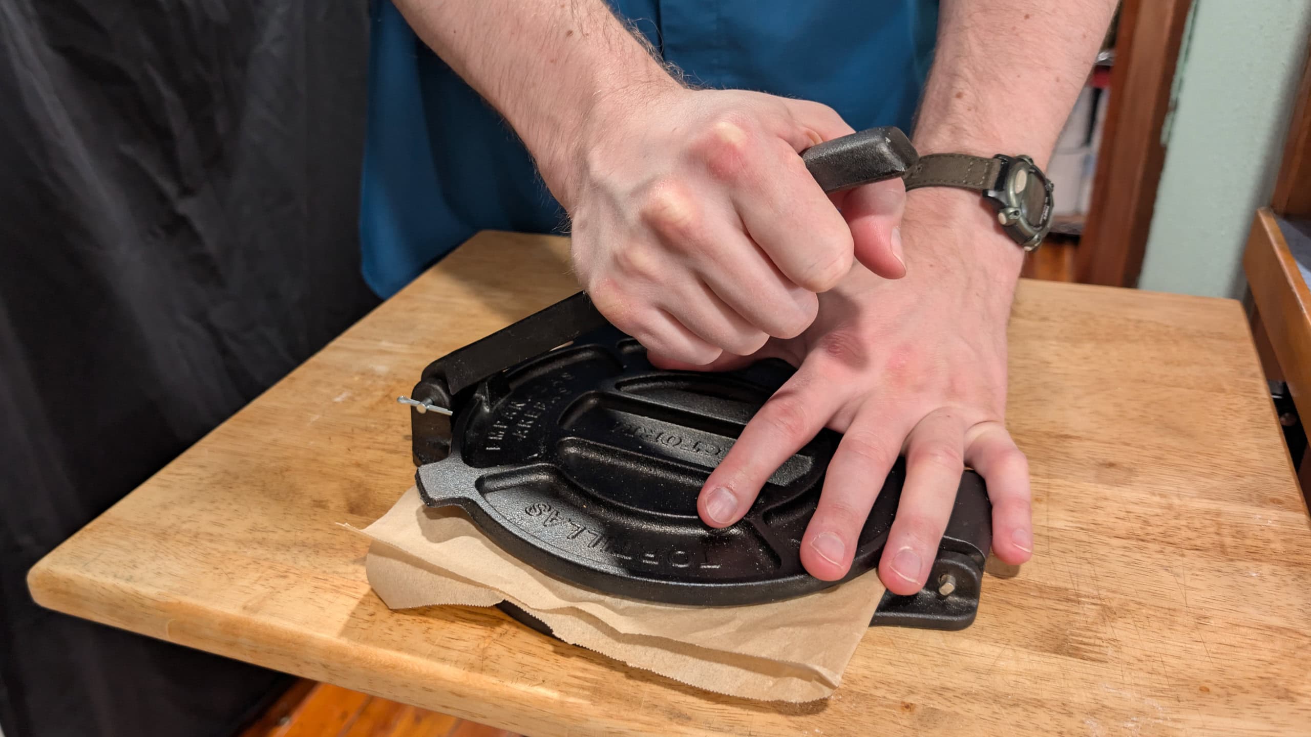 Adult hands working a tortilla press to create homemade tortillas