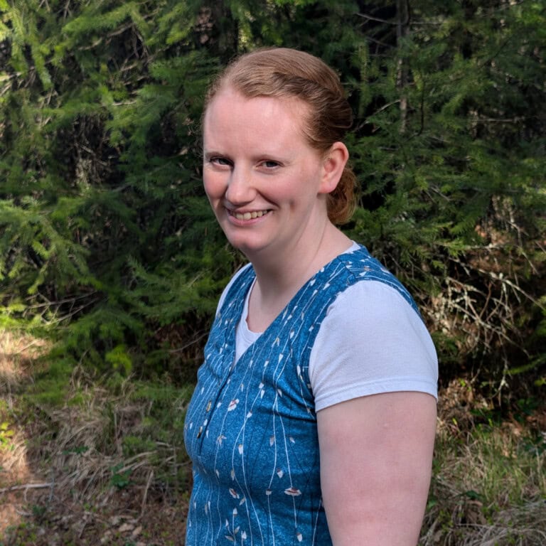 Photo of Ashley Johnson, homesteading mother, with a forest backdrop