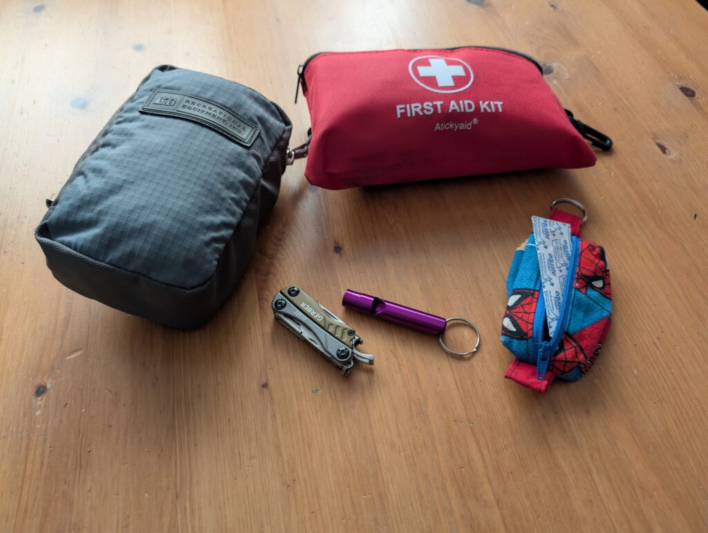EDC Pouches, first aid kit, knife, and whistle on a wooden table