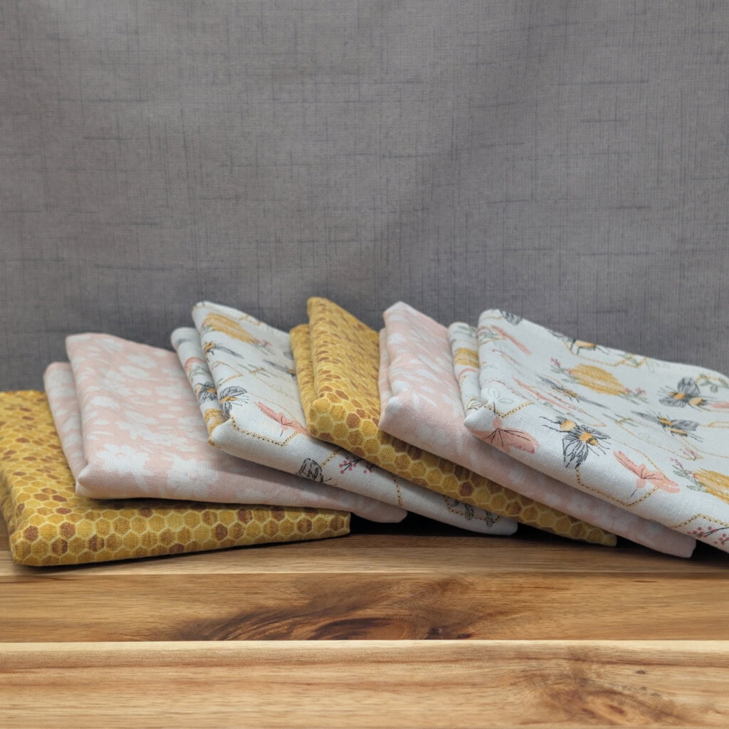 Set of fanned out reusable paper towels on wooden board in the honey bee pattern