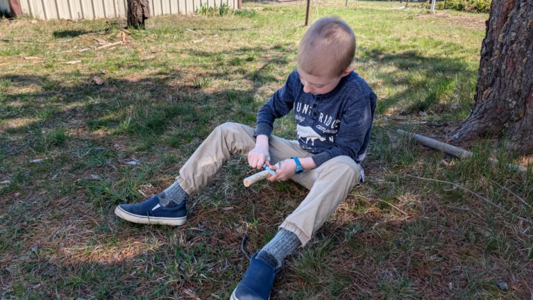 Child learning how to use the knife in his kids EDC kit safely