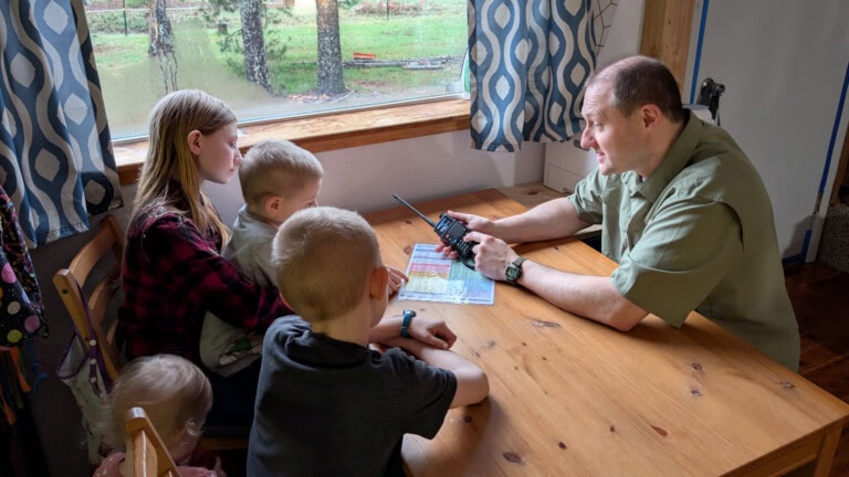 Father teaching younger children how to operate a portable radio during a practice drill