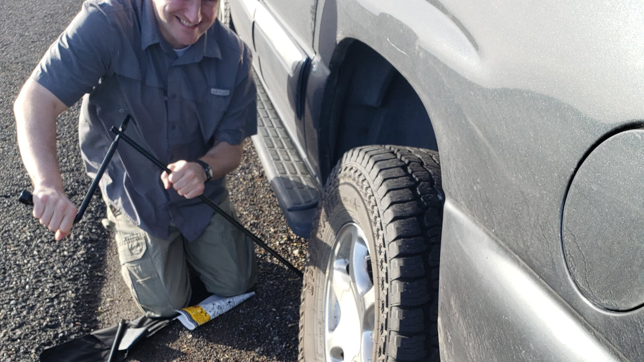 Man working jack under vehicle to change flat tire