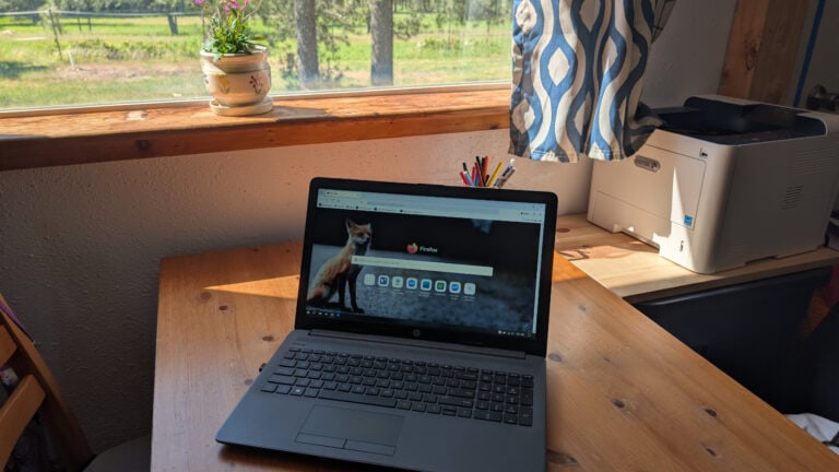 Computer with browser open to search engine on wood table, homestead fence in background