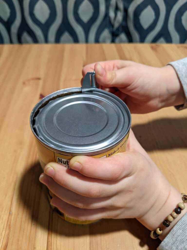 Child using P38 can opener to practice survival skills