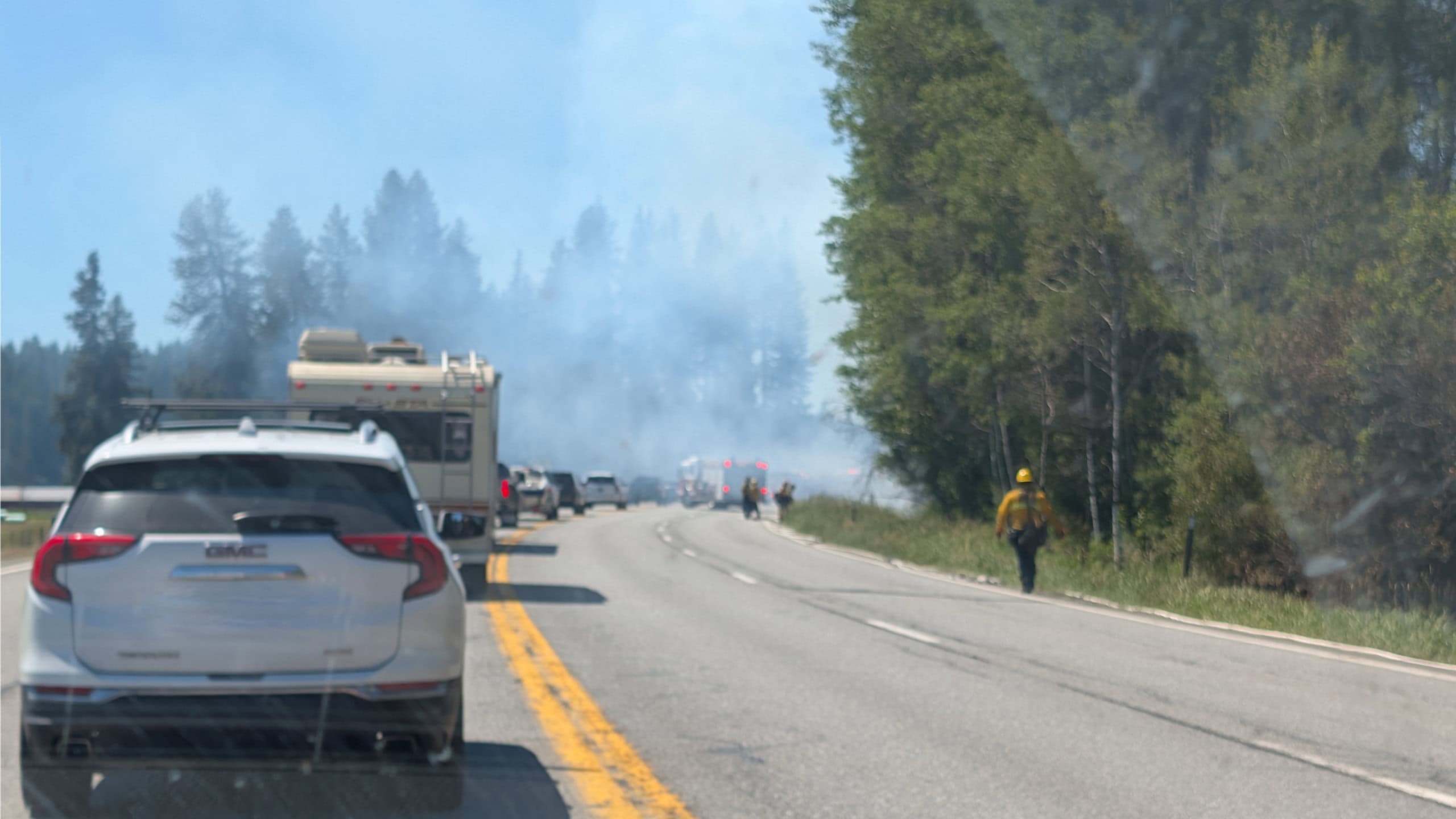 Vehicles driving around active wildfire on side of highway
