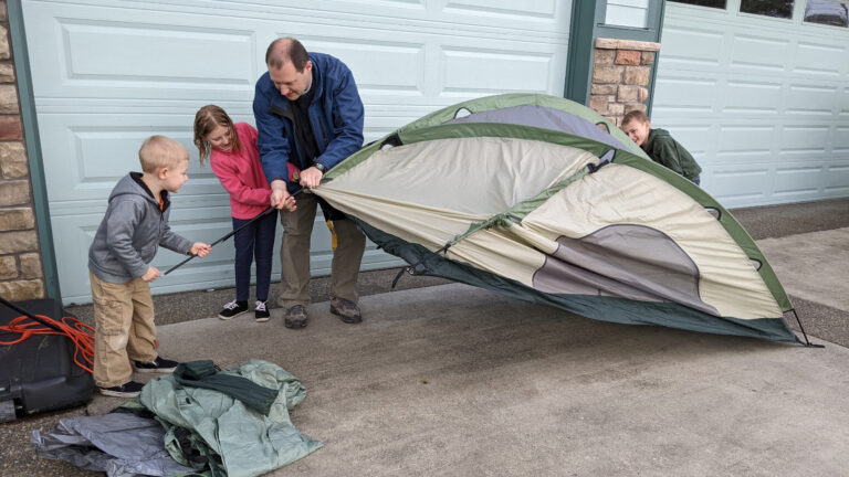 Father teaching kids how to set up a tent