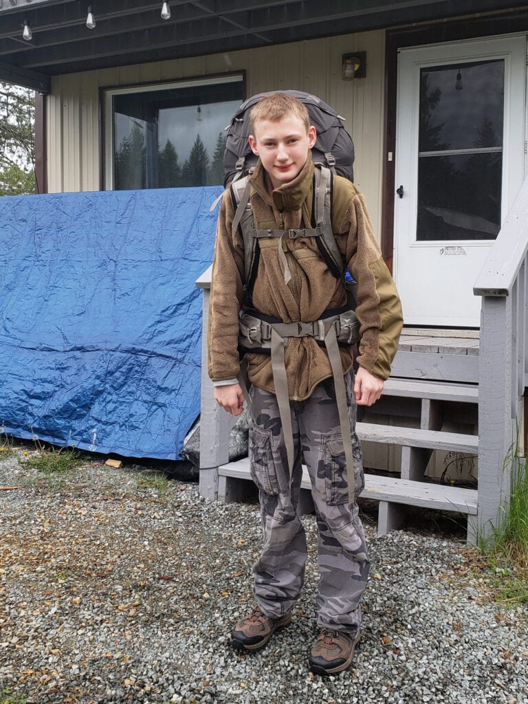 Teenage boy wearing hiking backpack testing the weight