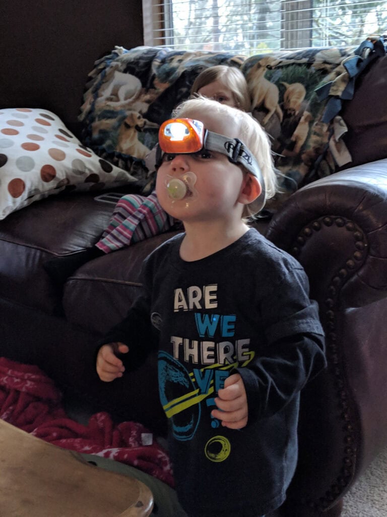 Toddler with adult headlamp trying it on and participating in preparedness exercise