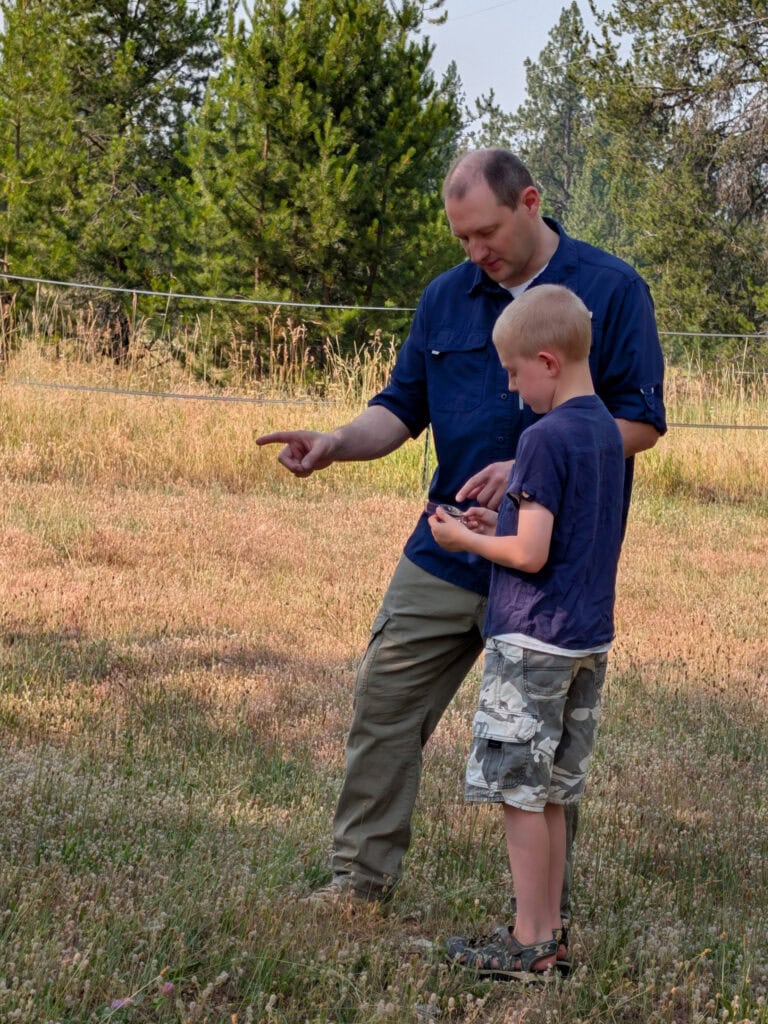 Dad teaching son how to navigate with a compass as part of homeschool education