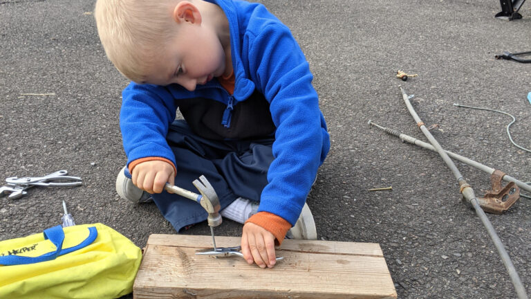 Young boy learning how to use a hammer